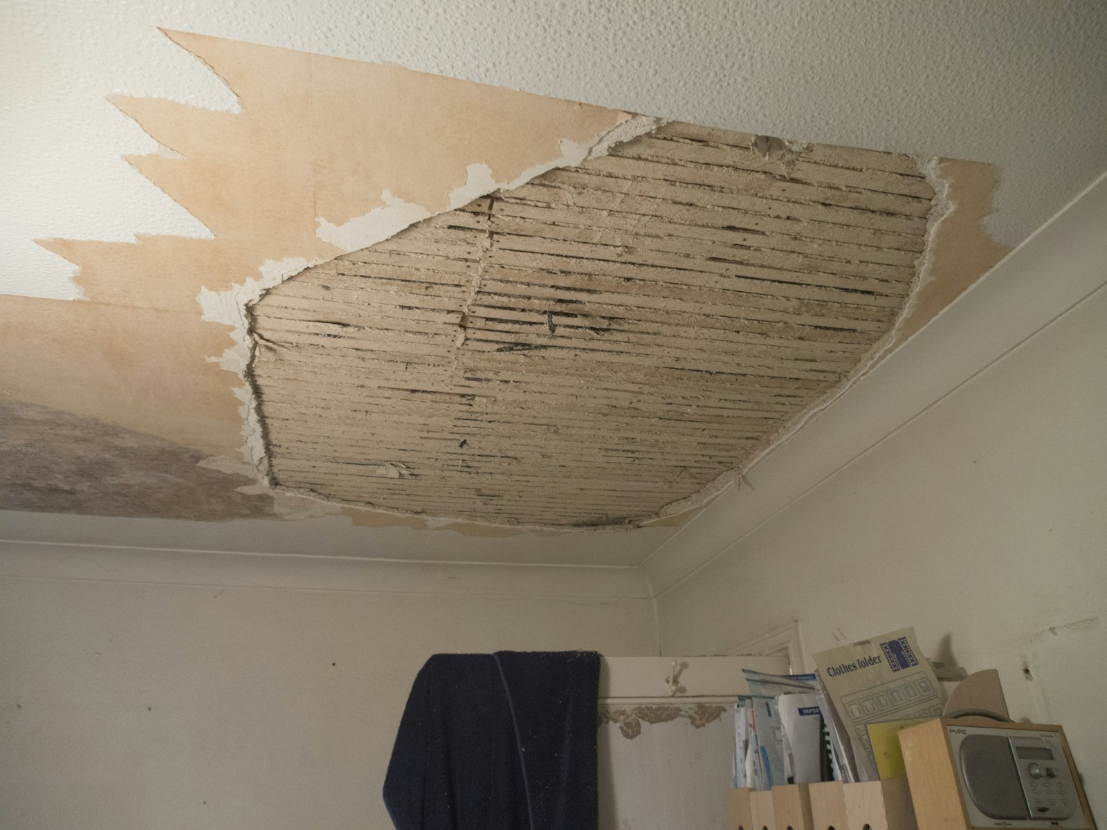 Room with water-damaged ceiling drywall torn away